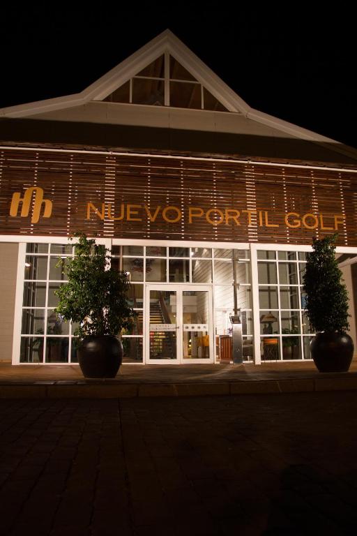 a lit up building with two plants in front of it at Hotel Nuevo Portil Golf in El Rompido