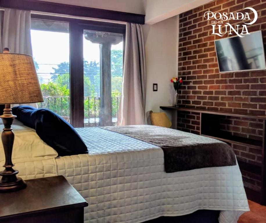 a bedroom with a bed and a brick wall at Hotel Posada de la Luna in Antigua Guatemala