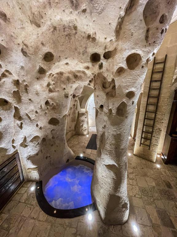a bathroom with a stone wall with a blue pool at La Suite Nella Roccia in Matera