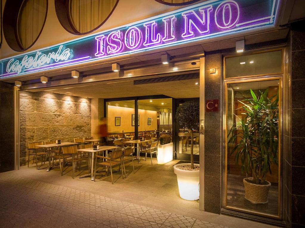 a restaurant with tables and a neon sign on the front at Hotel Isolino in O Grove