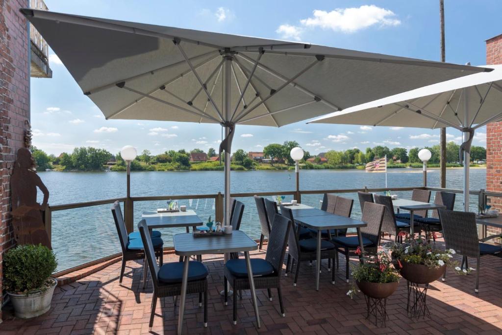 a patio with tables and chairs and an umbrella at Gästehaus Von Herzen in Lauenburg