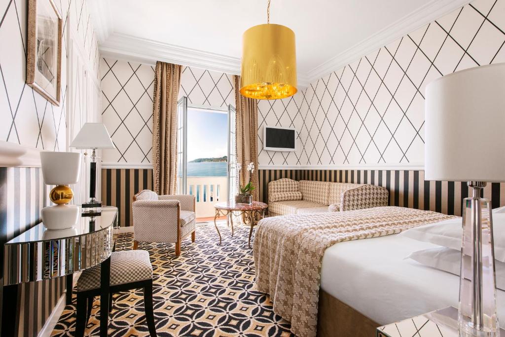 a hotel room with a bed and a living room at Hôtel Belles Rives in Juan-les-Pins
