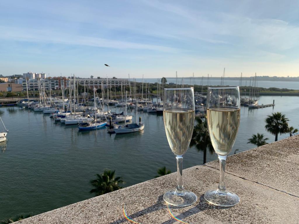 twee glazen wijn op een richel met uitzicht op een jachthaven bij Apartment Attico in Ayamonte