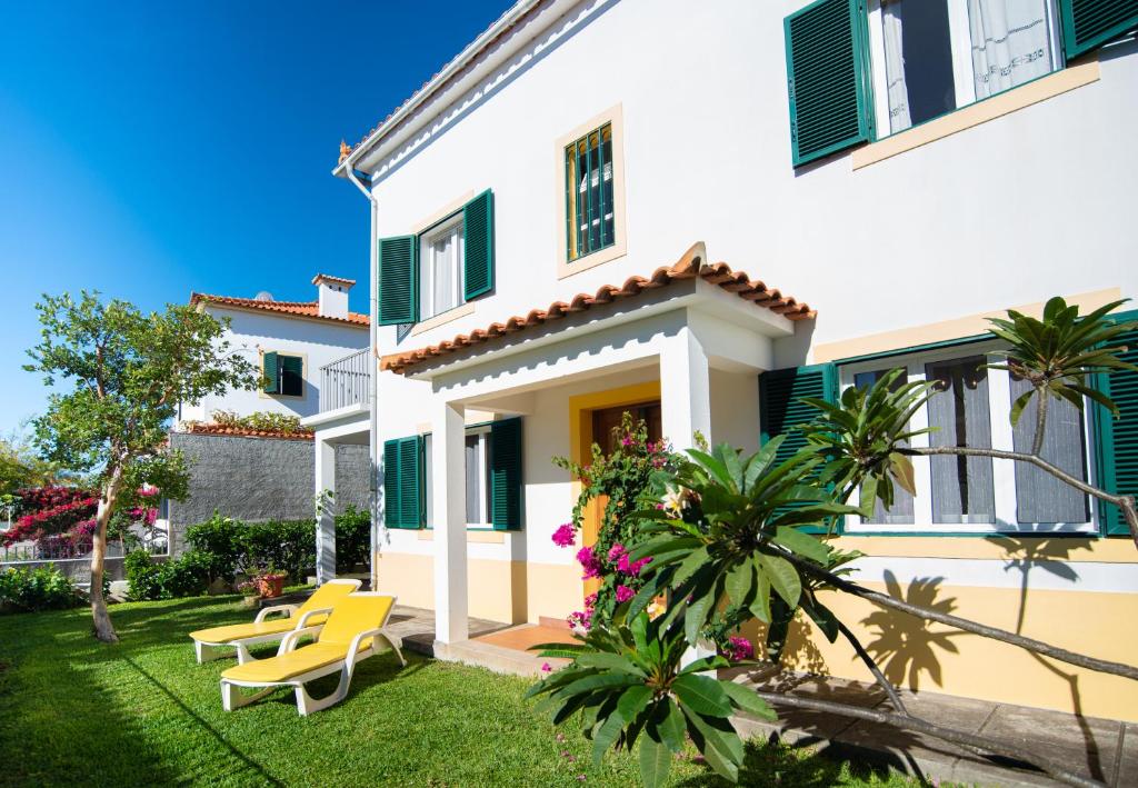 a house with green shutters and a yard at Villa Cosy Nook in Funchal