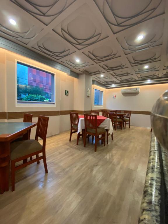 A bright dining room with dressed tables, large windows and decorative ceiling panels.