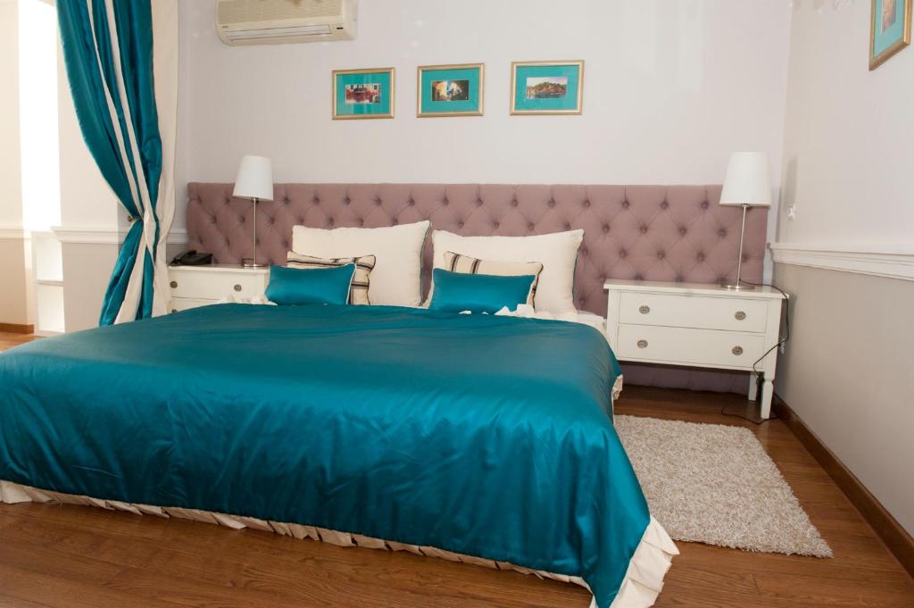 1 dormitorio con 1 cama azul y 2 mesitas de noche en Boutique Vila Paradis, en Deva