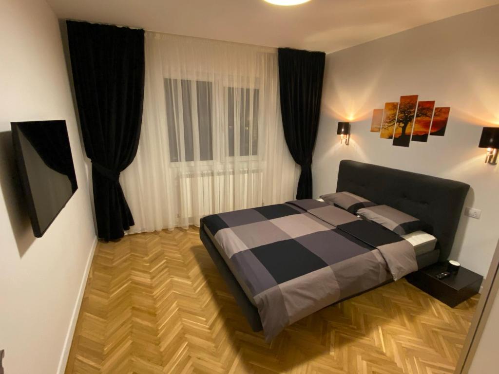 a bedroom with a bed and a window with black curtains at Center Loft in Buzău