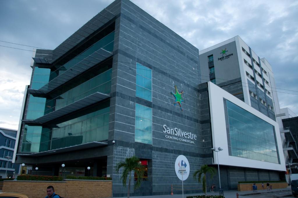 un grand bâtiment en verre avec un panneau devant lui dans l'établissement Hotel San Silvestre, à Barrancabermeja