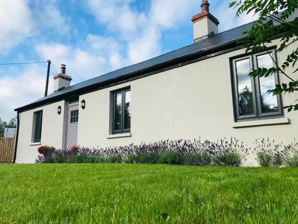 a white house with windows and a green lawn at Lavender Cottage - 2 Bedroom Home in Newbridge