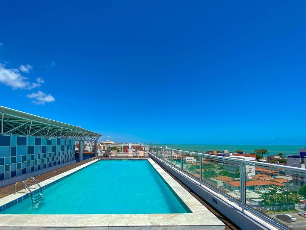 a swimming pool on top of a building with the ocean at Hotel Caiçara João Pessoa in João Pessoa