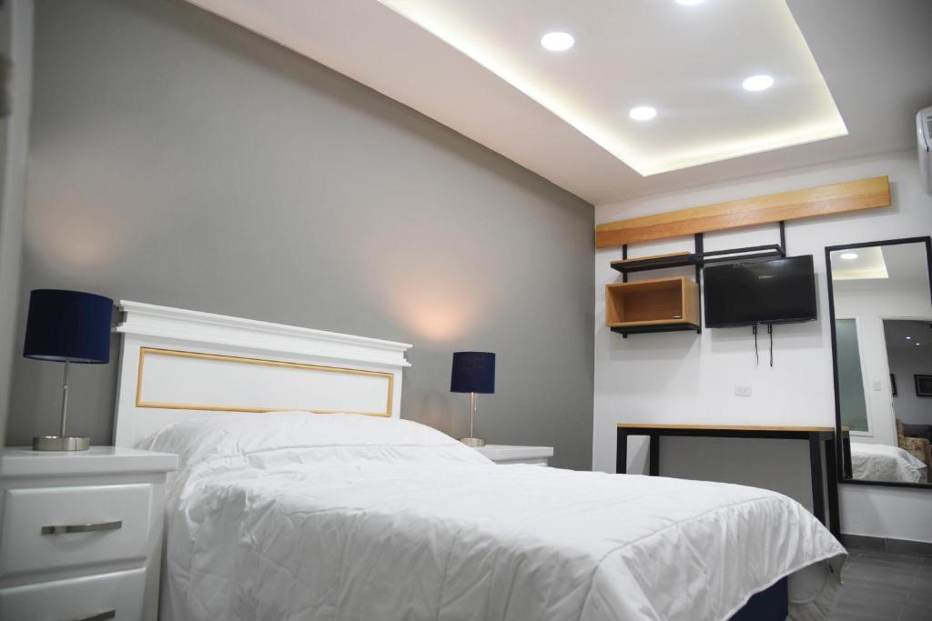 1 dormitorio con 1 cama blanca y TV en la pared en Casa moderna equipada como hotel Habitación 2 F, en Monterrey