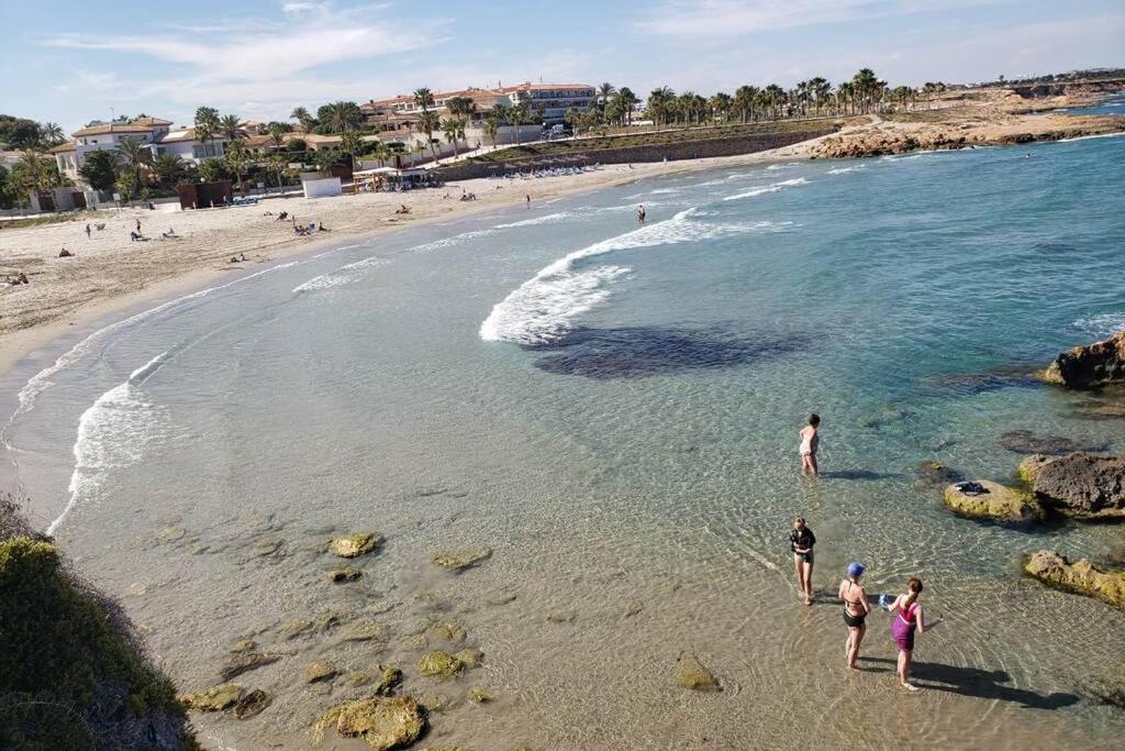 a group of people standing in the water on a beach at Playa Flamenca Splendid apartment on the beach in Alicante