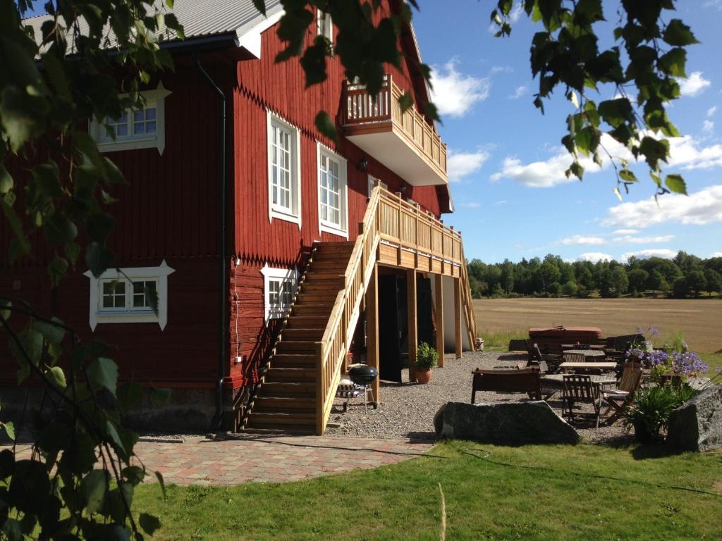 ein großes rotes Gebäude mit einer Treppe und einer Terrasse in der Unterkunft Låsta Gårdshotell in Strängnäs