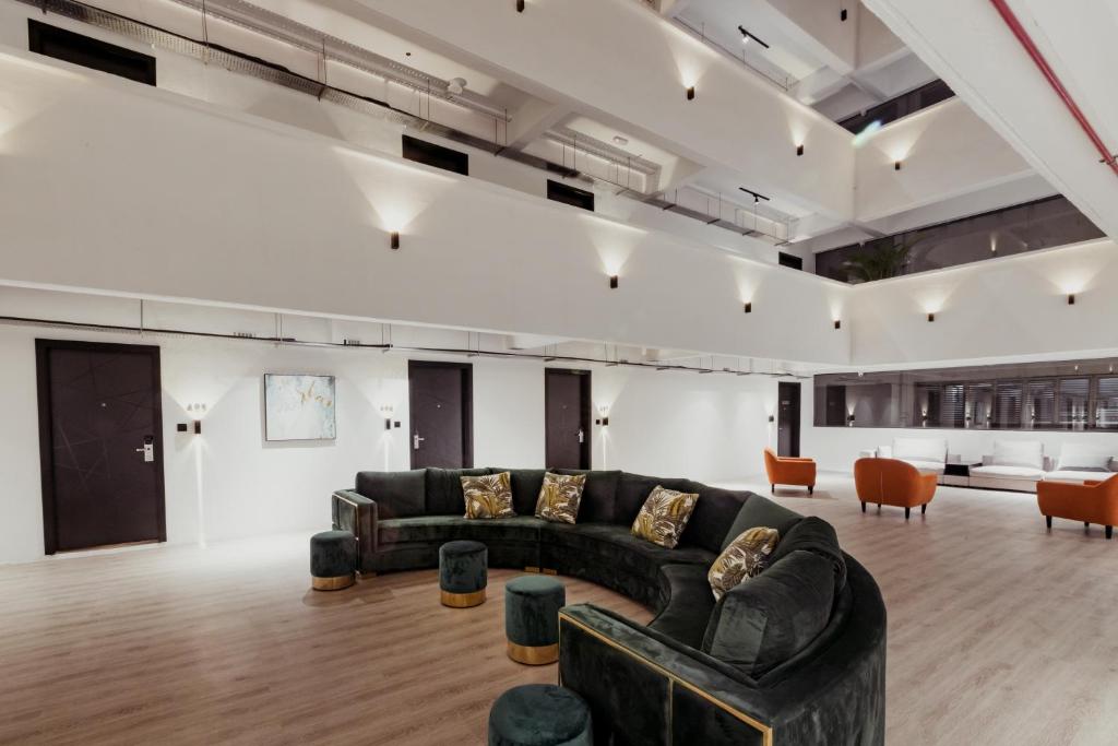 A spacious atrium lounge with a curved black sofa and orange armchairs.