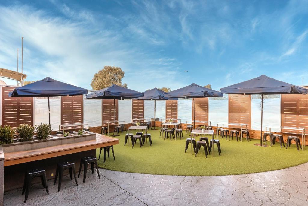 a patio with tables and chairs with blue umbrellas at Dorset Gardens Hotel in Croydon