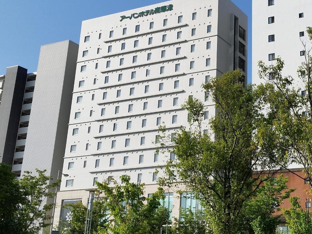 un edificio blanco alto con una señal de aazon en él en Urban Hotel Minami Kusatsu en Kusatsu