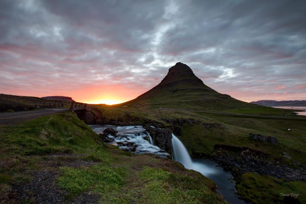 una puesta de sol sobre una montaña con un río en Búlandshöfði í Grundarfirdi, en Grundarfjordur