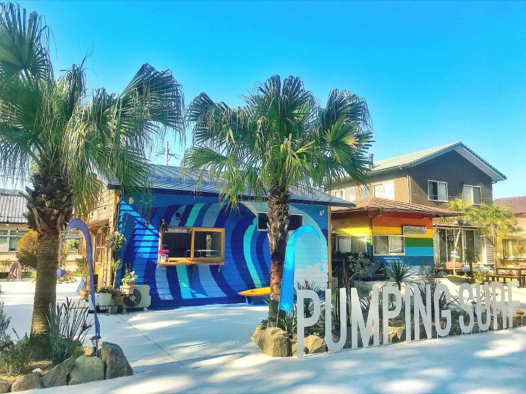 a blue building with palm trees in front of it at Tabist Pumping Surf in Hyuga