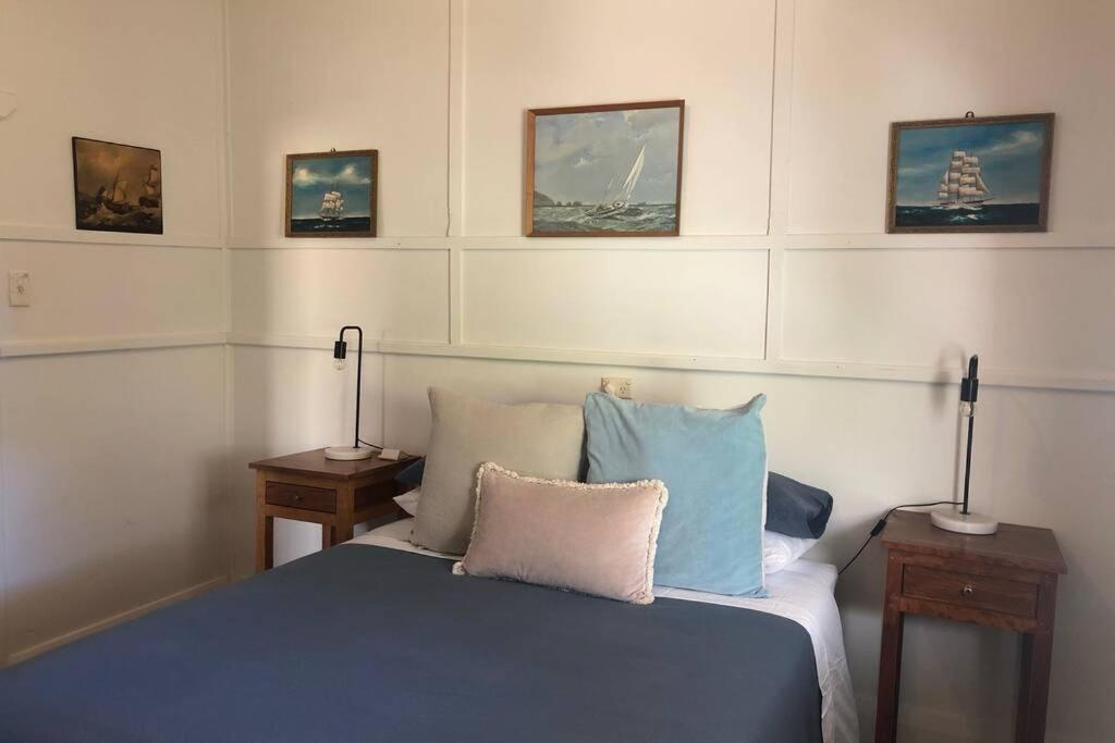 Schlafzimmer mit einem Bett mit Kissen und Bildern an der Wand in der Unterkunft Twilight Cottage in Esperance
