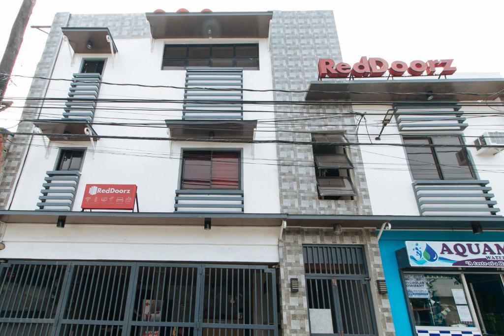 un edificio bianco con un cartello rosso di RedDoorz near Christ the King Medical Center a Manila