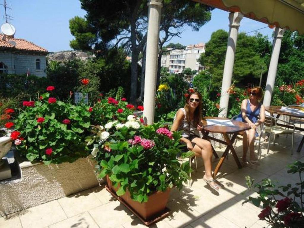 dos mujeres sentadas en una mesa en un jardín con flores en House Boninovo, en Dubrovnik