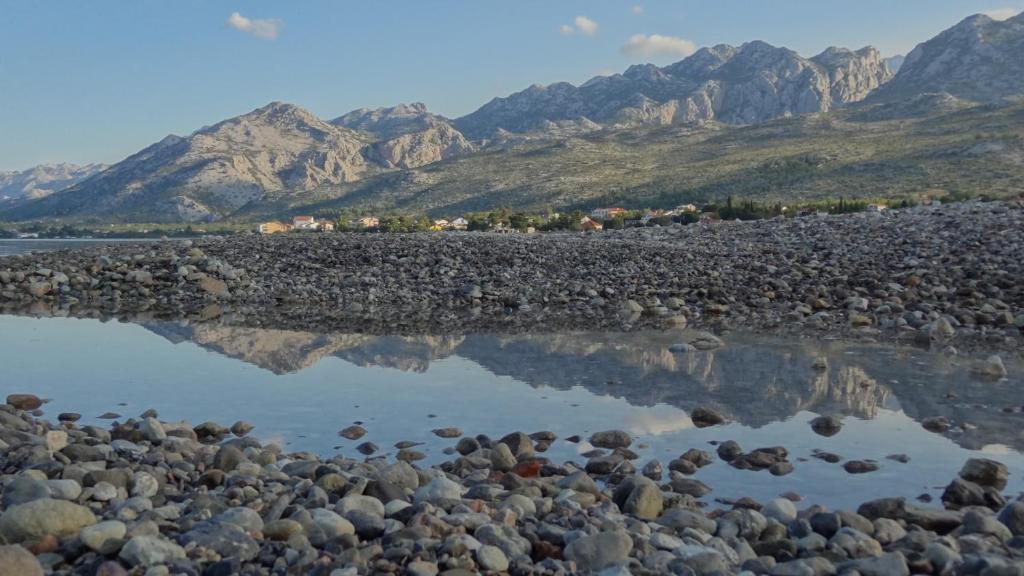un reflejo de una orilla rocosa con montañas en el fondo en Apartments Ante 1306, en Seline