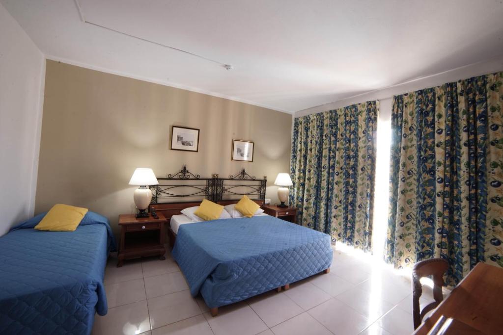a bedroom with two beds and a window at Topaz Hotel in St. Paul's Bay