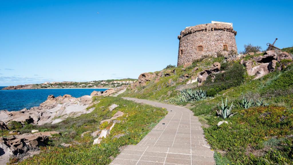 un camino a un castillo en una colina junto al océano en Welcomely - Piedra del Sol, en Portoscuso