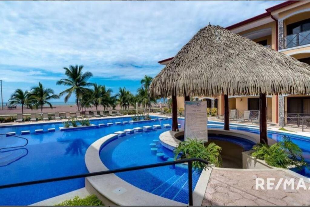 un complexe doté d'une grande piscine avec un parasol dans l'établissement 777J Beachfront Luxury Condo 3 BR/2.5BA Near SJO - Jaco Beach, à Jacó