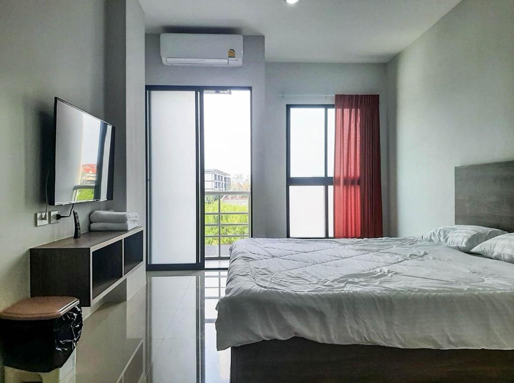 a bedroom with a bed and a tv and a window at AFP Residence Hotel in Bangkok