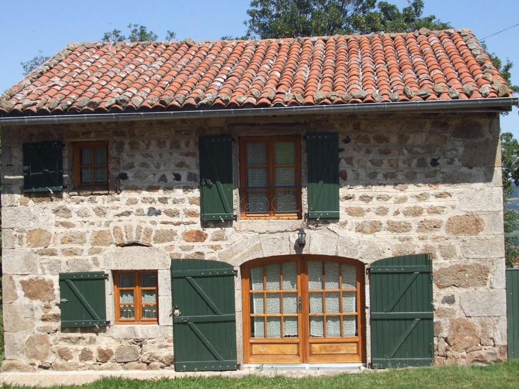una antigua casa de piedra con ventanas con persianas verdes en Beautiful holiday home with mountain view, en Sauvain
