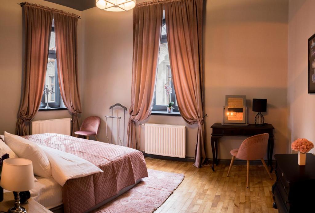 a bedroom with a bed and a desk and windows at Apartament Podcienie z tarasem Bielsko-Biała Old Town in Bielsko-Biała