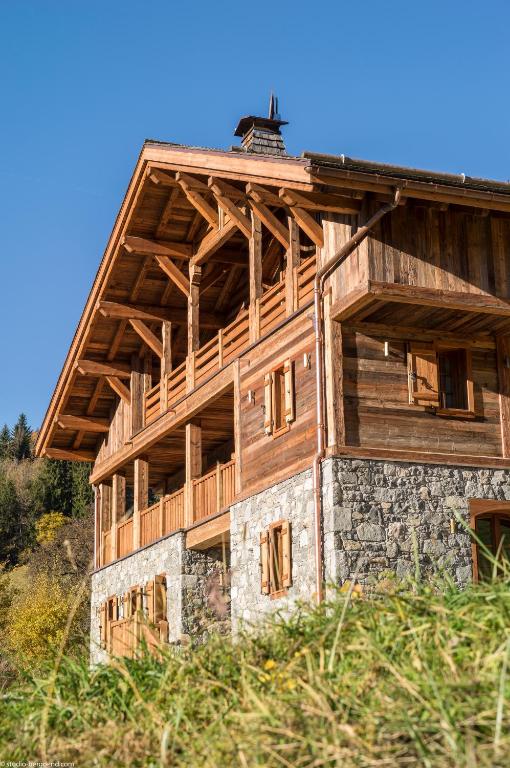 un grand bâtiment en bois avec un toit dans l'établissement MGM Hôtels & Résidences - Chalet La Ferme de Juliette, au Grand-Bornand