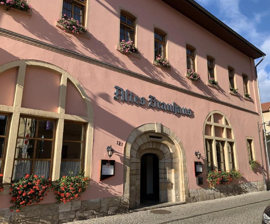 Un bâtiment rose avec des fleurs sur son côté dans l'établissement Altes Brauhaus, à Weißenfels