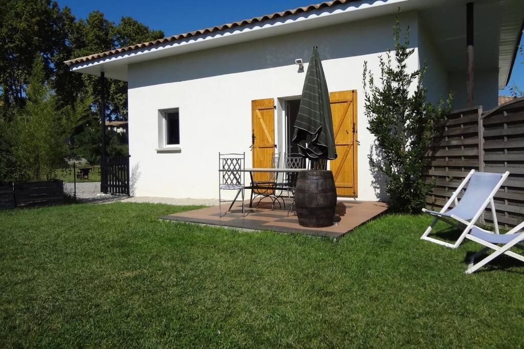 een klein wit huis met een tafel en twee stoelen bij Maison calme avec jardin et parking privés in Marsillargues