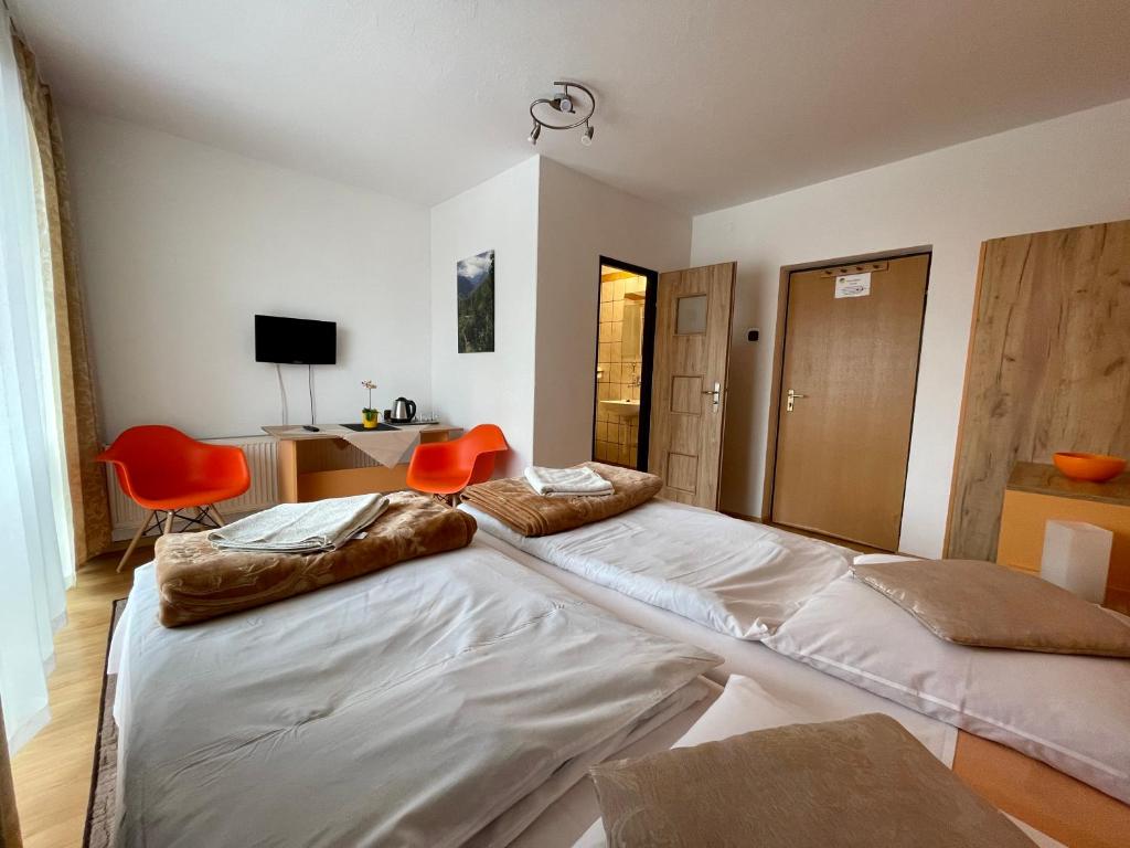 two large beds in a room with orange chairs at Dom Wczasowy Anna in Rabka-Zdrój