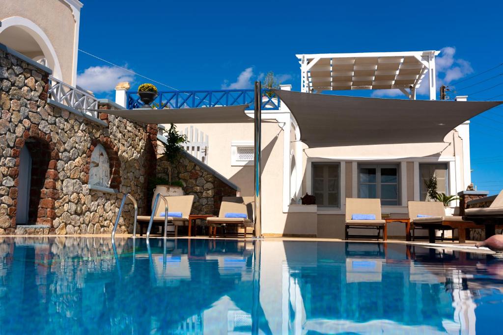 a swimming pool with chairs and a house at Hotel Thira in Fira