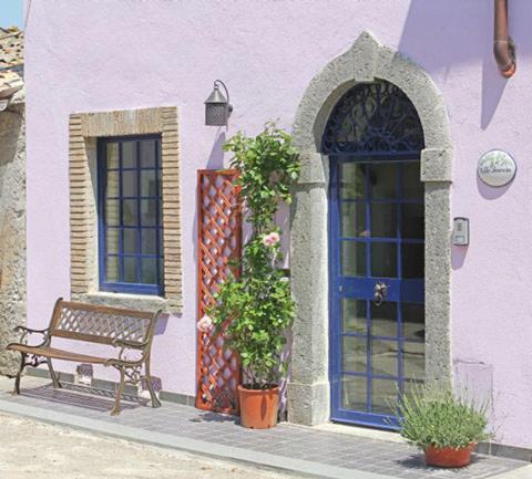 un banco sentado frente a un edificio púrpura en Casa Amarosa, en San Michele in Teverina