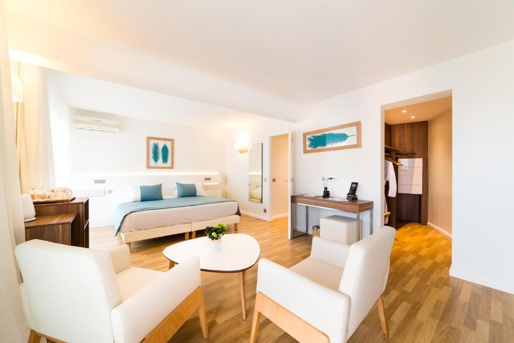 a hotel room with a bed and a table and chairs at Hôtel Hélios in Juan-les-Pins