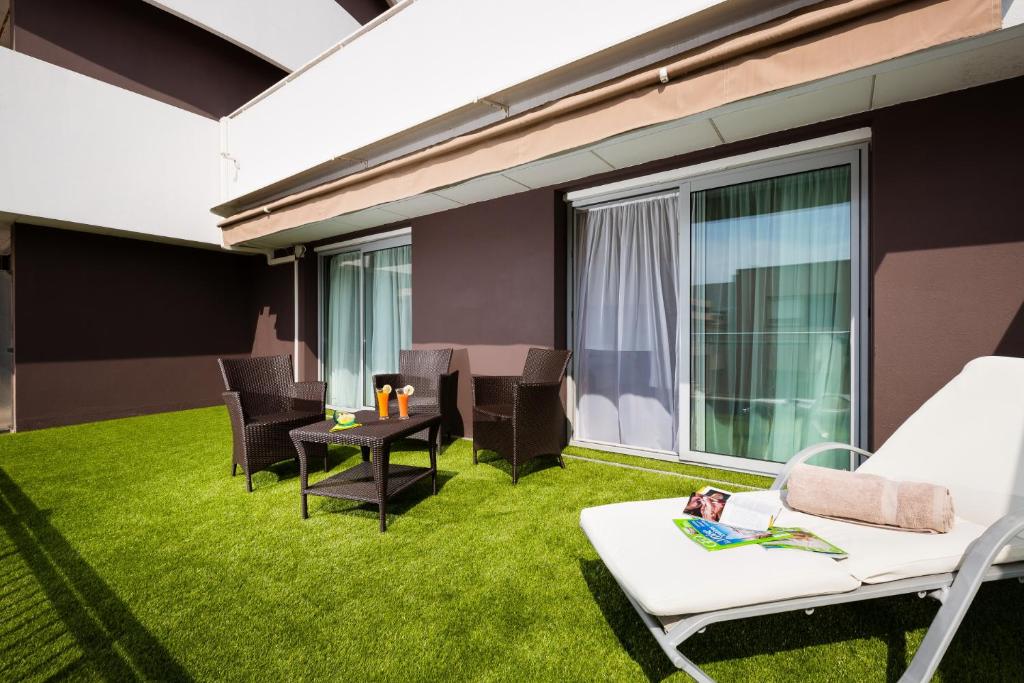a living room with green grass and chairs and a table at Hôtel Hélios in Juan-les-Pins