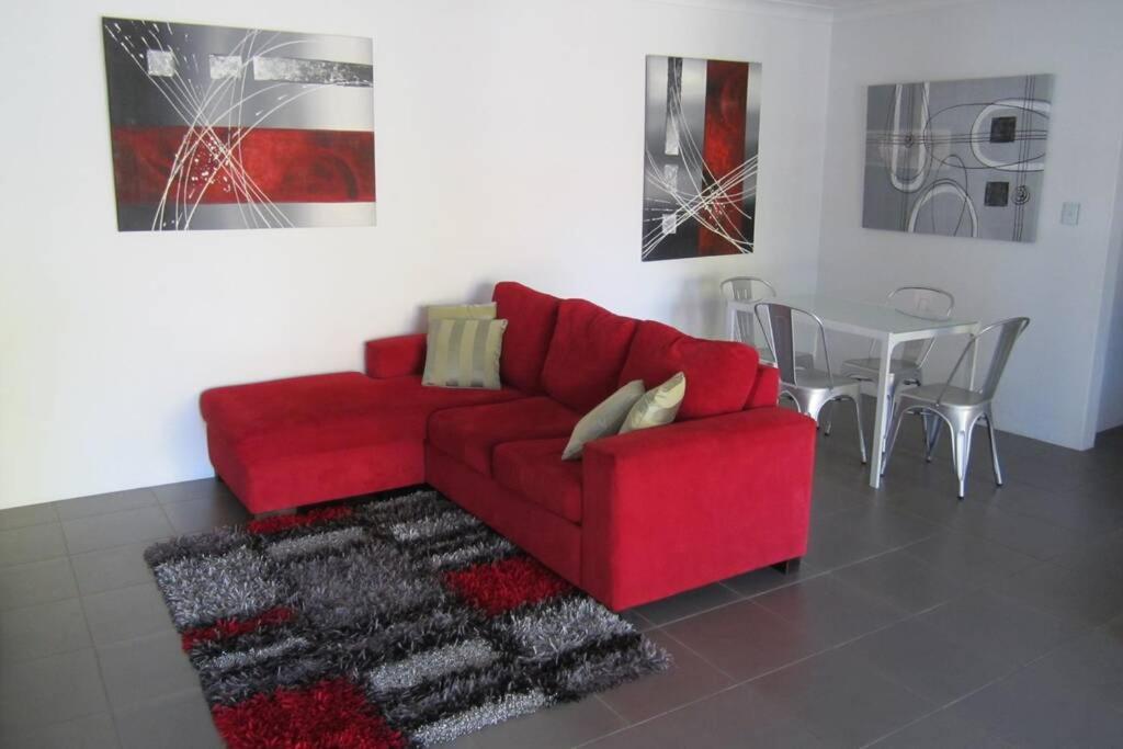 a red couch in a living room with a table at Cronulla Beach Elanora Gardens in Cronulla