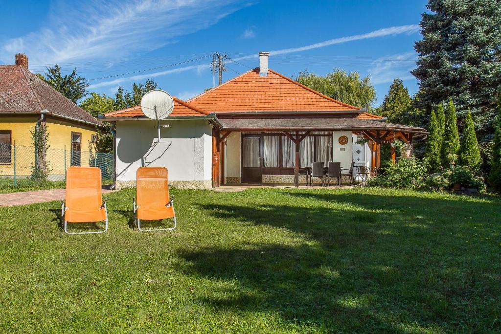 zwei orangefarbene Stühle im Hof eines Hauses in der Unterkunft Familia Nyaraló 3 in Balatonmáriafürdő
