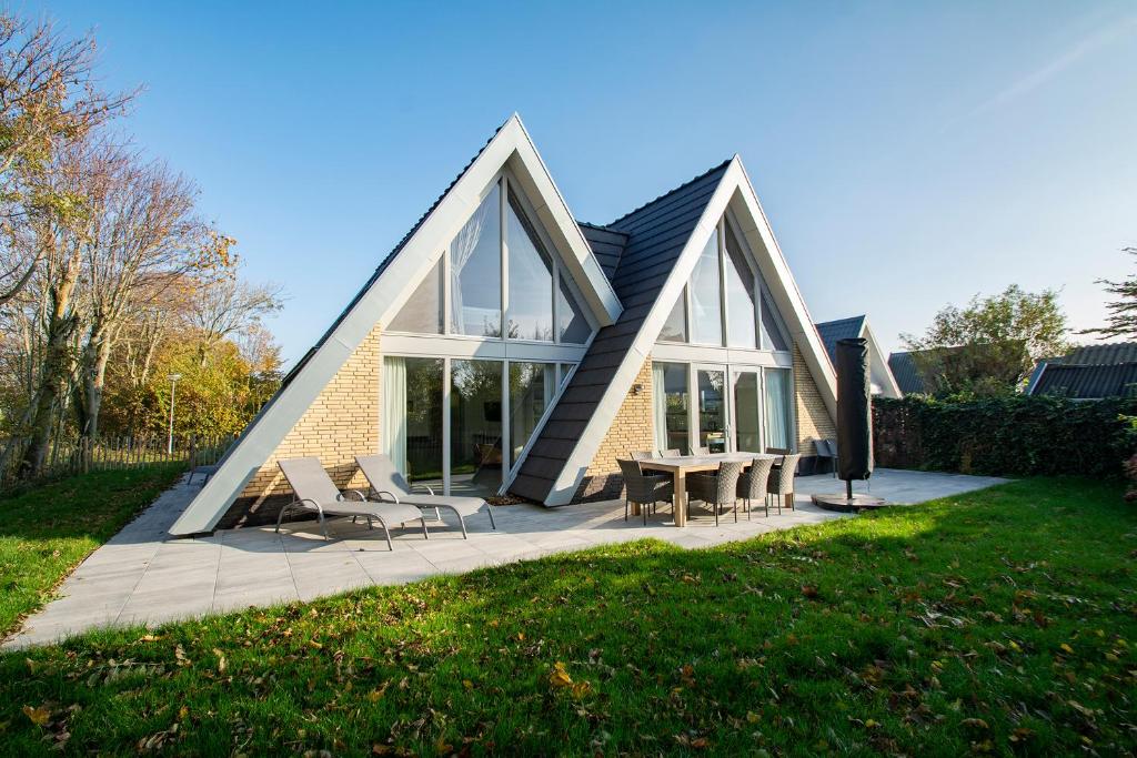 een huis met een driehoekig dak met stoelen en een tafel bij Sandepark 171 - Groote Keeten in Callantsoog