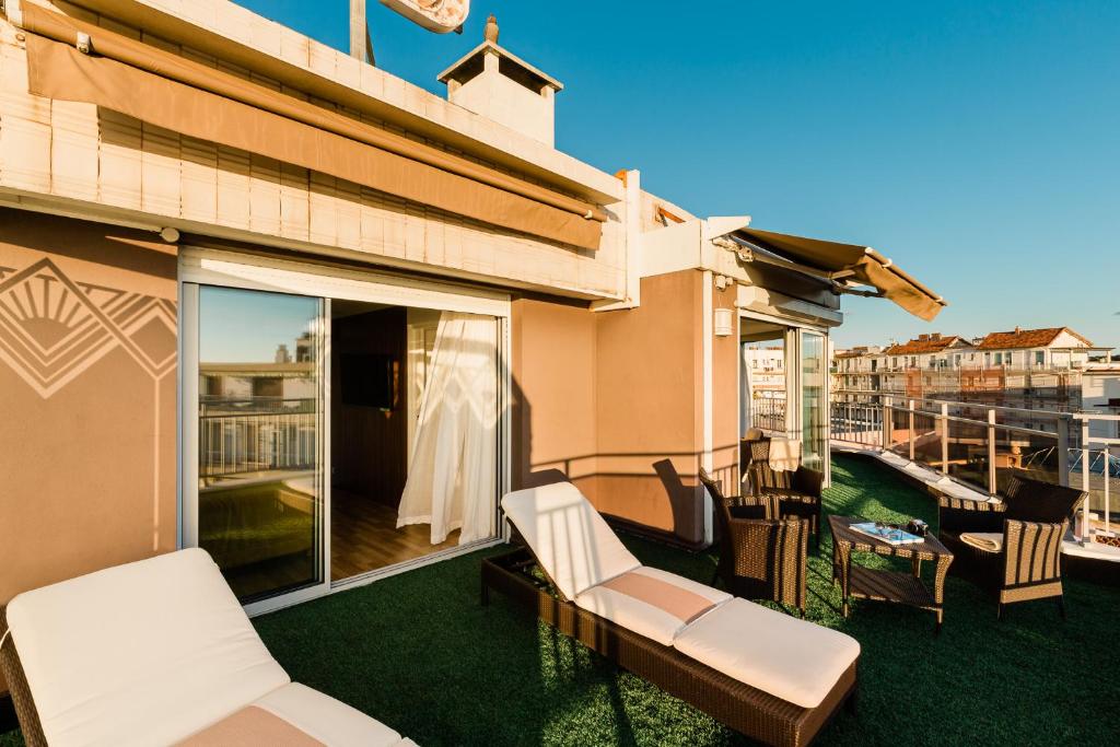 a patio with white chairs and a balcony at Hôtel Hélios in Juan-les-Pins