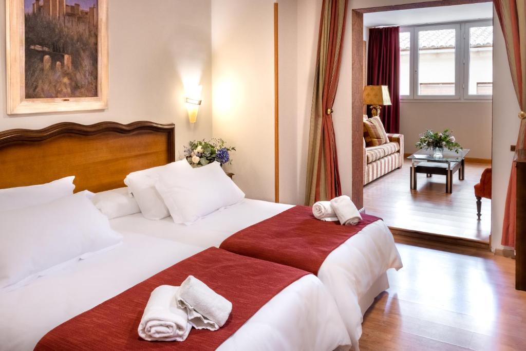 Hotel Reina Cristina في غرناطة: غرفة فندق بسرير كبير عليها مناشف