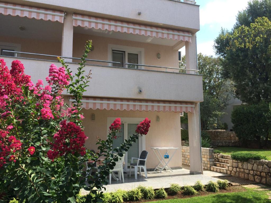 une maison avec un balcon et des fleurs roses dans l'établissement Apartments Malinska - apartment 3, à Malinska