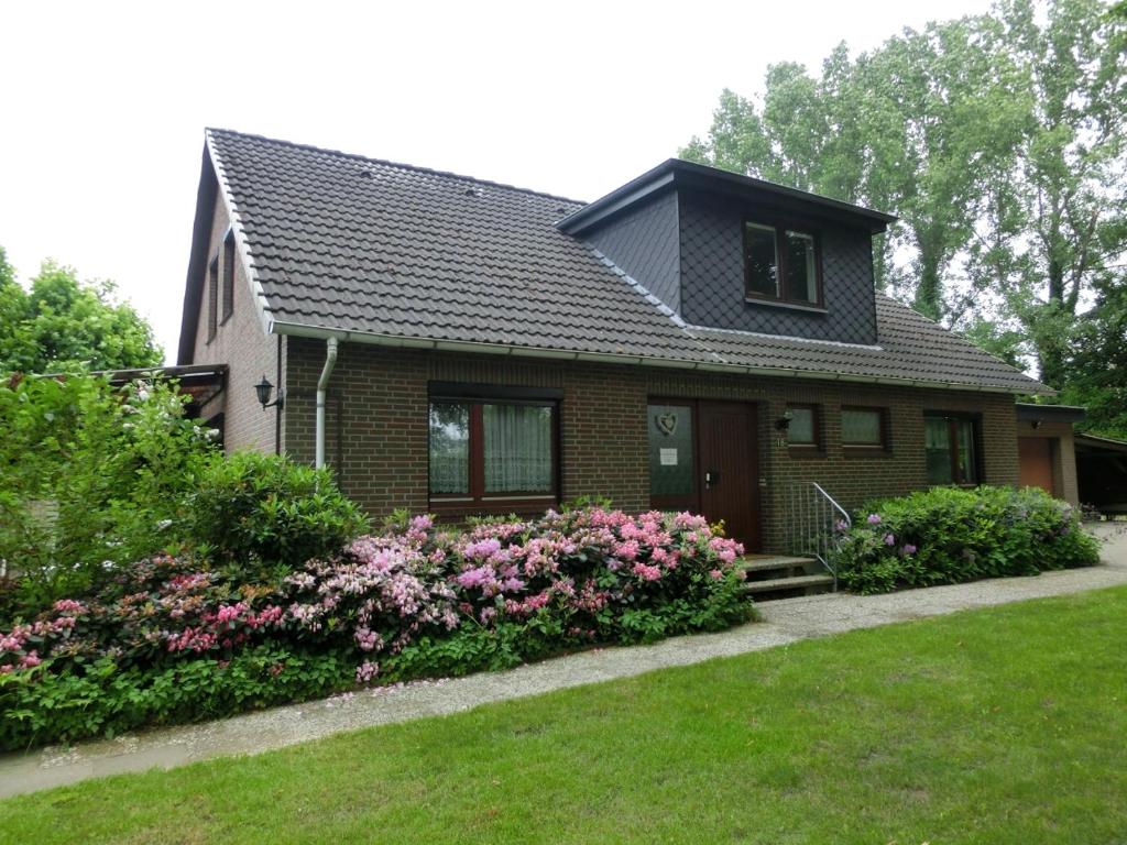 a small house with pink flowers in the yard at Ferienwohnung Wiesenweg in Bad Bederkesa