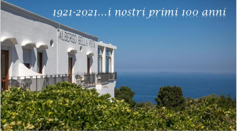 a white building with trees and the ocean in the background at Hotel Bellavista in Anacapri