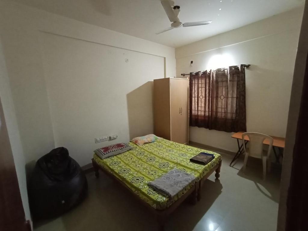 Habitación pequeña con cama y nevera. en Professionals Pride PG en Bangalore