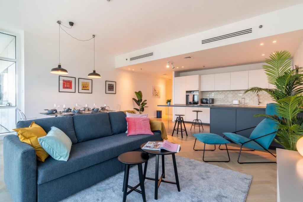 a living room and kitchen with a blue couch at The Smart Concierge - Mag 218 in Dubai